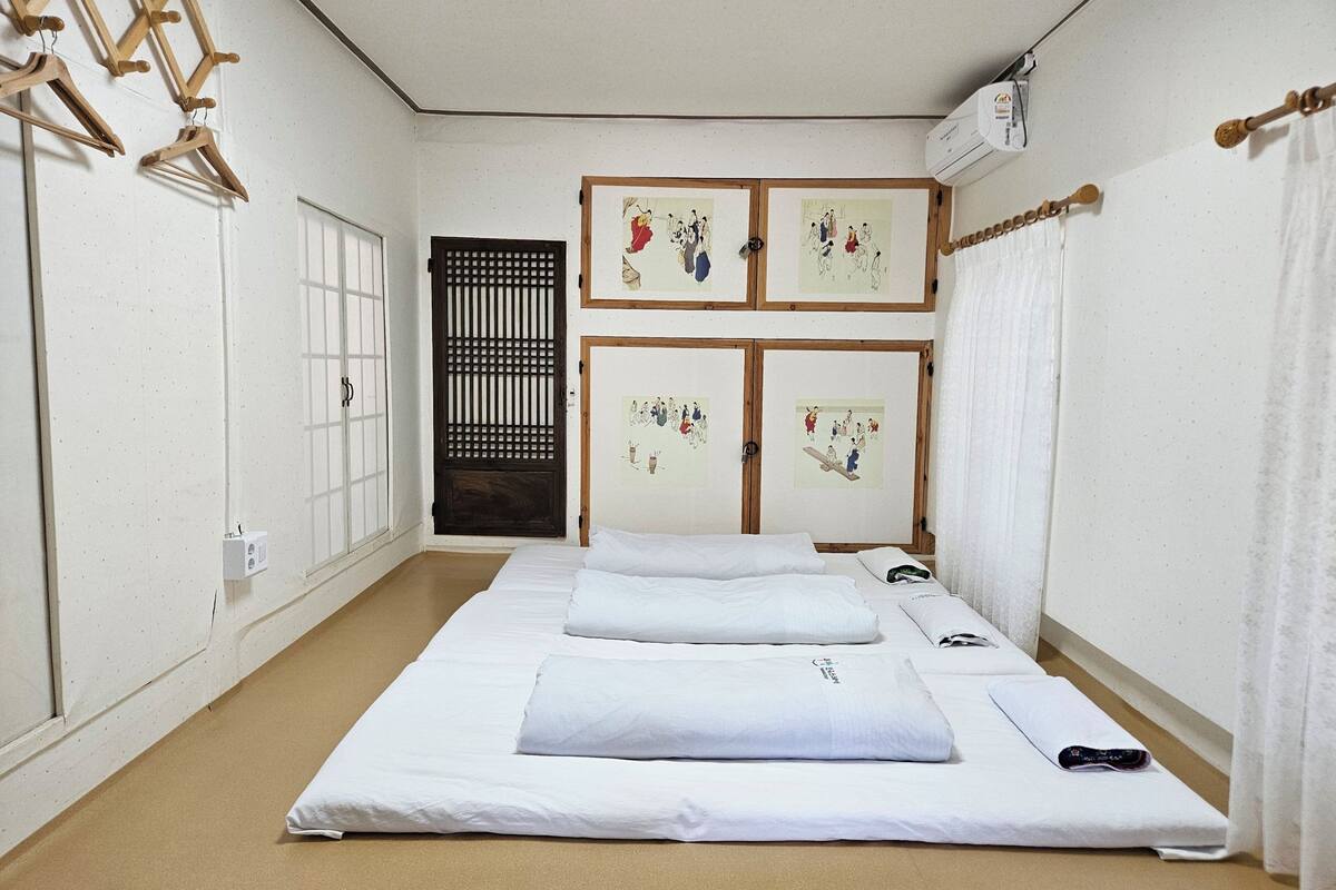 A room with a bed, a wardrobe, a window, and a door.