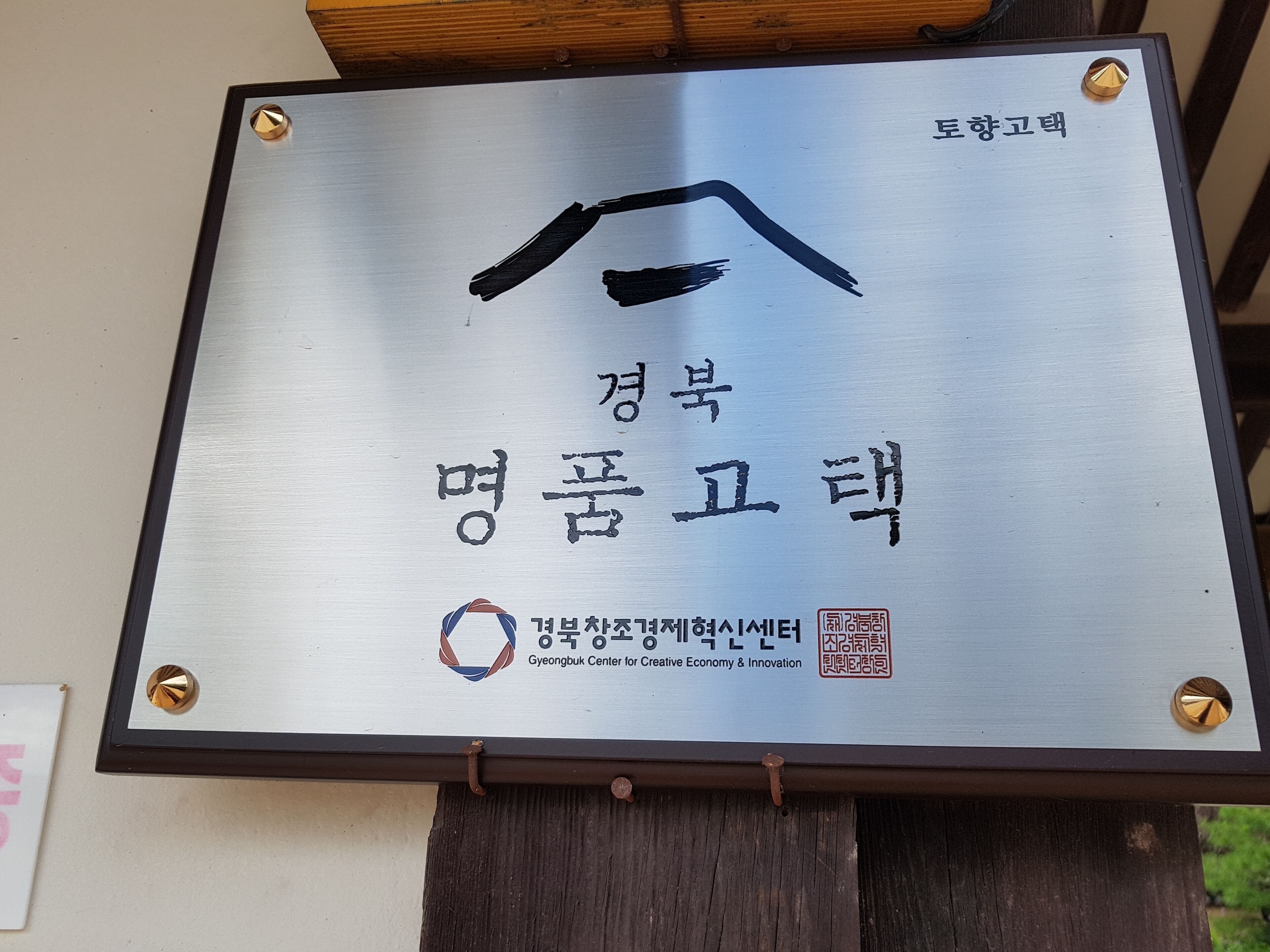 A metallic plaque with Korean text and a logo for the Gyeongbuk Center for Creative Economy & Innovation.