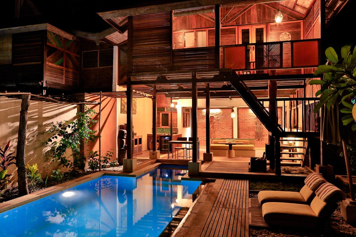 Een modern huis met een zwembad, een houten terras en een gezellige zithoek.