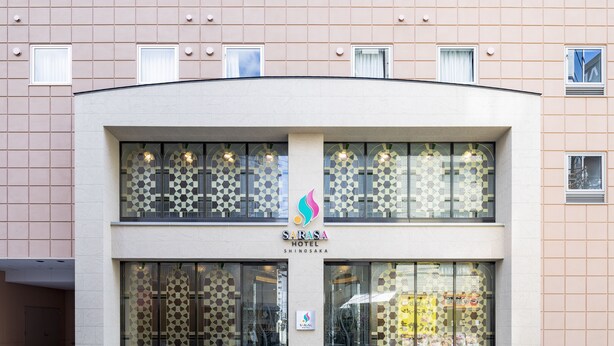 A hotel with a modern facade, large windows, and a logo in the center. - SARASA HOTEL Shin-Osaka (Osaka)