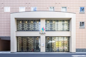 A hotel with a modern facade, large windows, and a logo in the center. - SARASA HOTEL Shin-Osaka (Osaka)