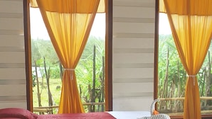 A room with two beds, each with a red and white bedspread, and yellow curtains.