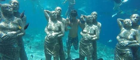 Un grupo de estatuas sumergidas con buzos cerca.