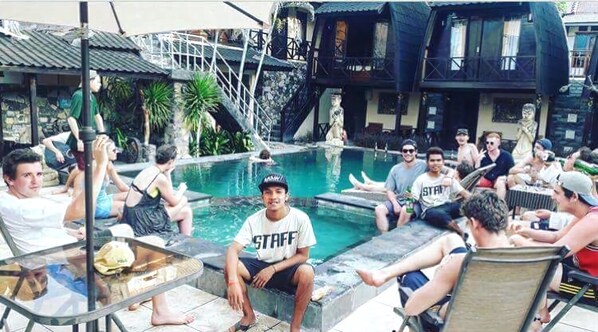 A group of people around a pool with a metal staircase and a building in the background. - Bale Sasak (Gili Trawangan)
