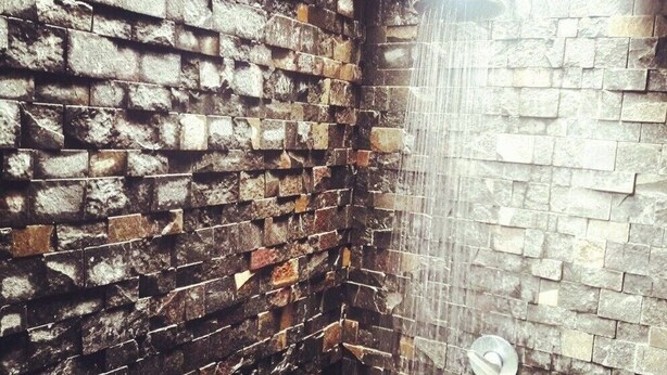 A corner of a room with a brick wall and a stone wall with a shower. - Bale Sasak (Gili Trawangan)