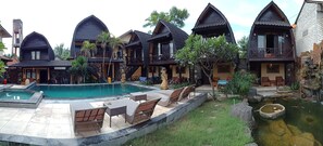 A resort with multiple chalet-style buildings, a swimming pool, outdoor seating, and a small pond. - Bale Sasak (Gili Trawangan)