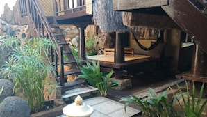 A rustic outdoor area with a wooden staircase, stone walls, and various plants. - Bale Sasak (Gili Trawangan)