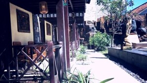 An outdoor area with a covered seating area, stone statues, and potted plants. - Bale Sasak (Gili Trawangan)