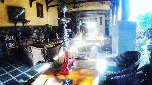A cozy indoor setting with a wooden bar, a hookah, and wicker furniture. - Bale Sasak (Gili Trawangan)