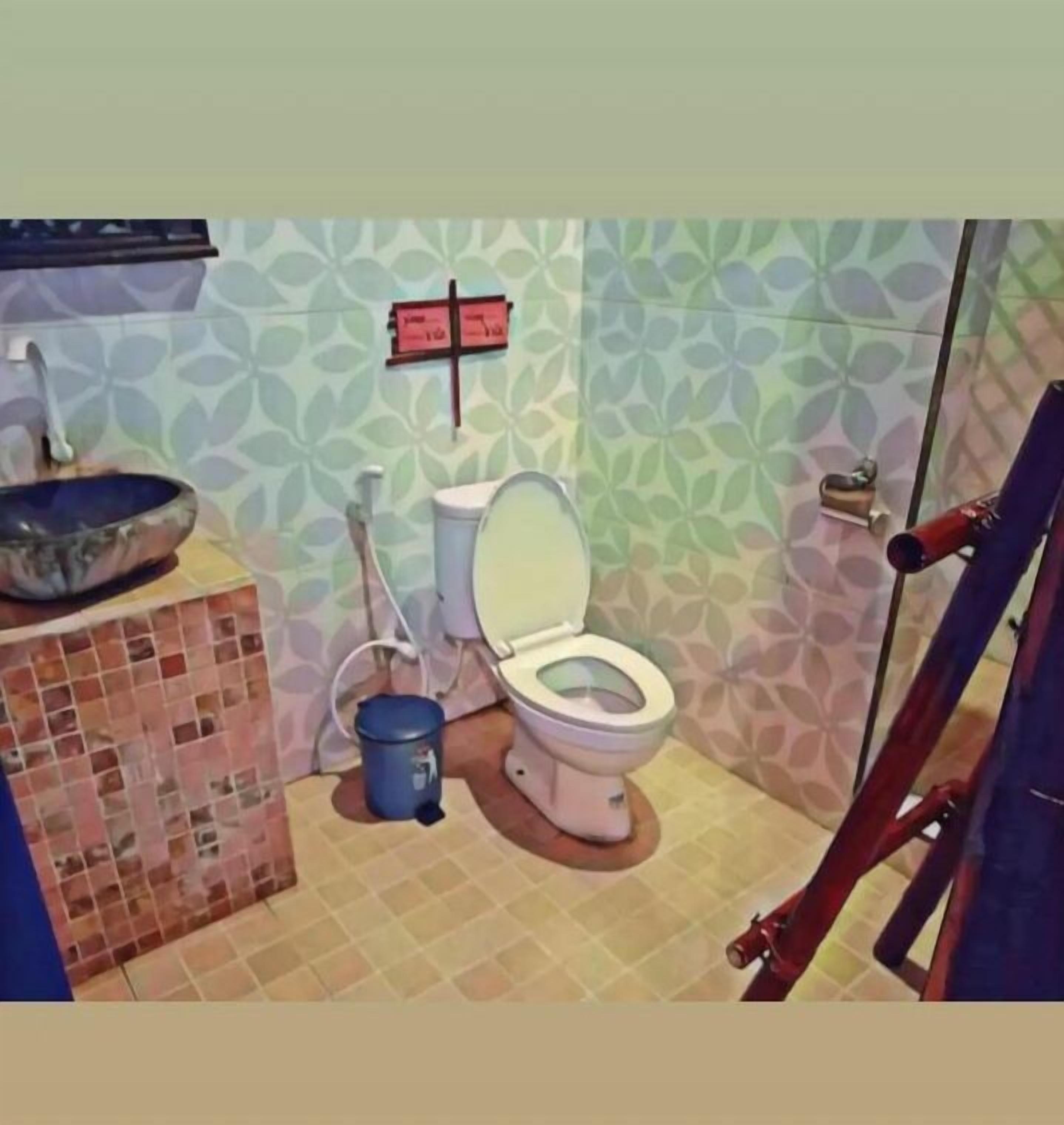 Ein Badezimmer mit Toilette, Waschbecken und einer blauen Mülltonne.