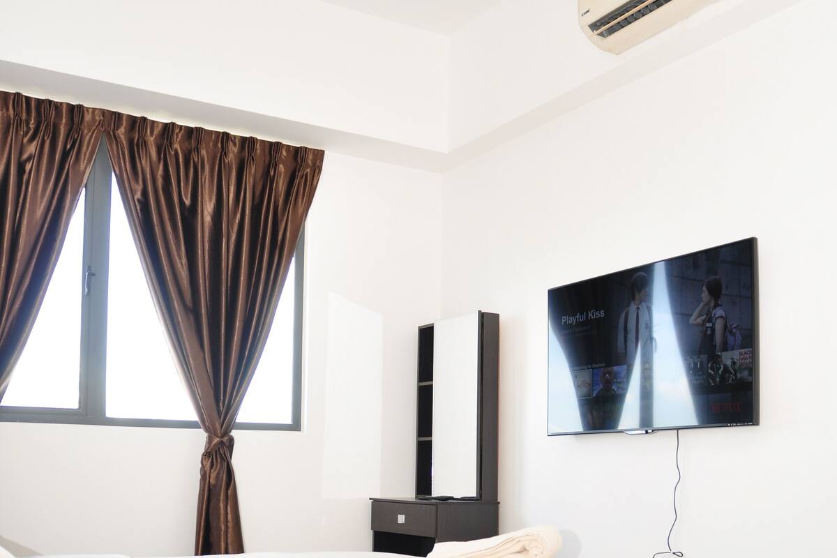 A modern bedroom with a bed, a TV, and an air conditioning unit.