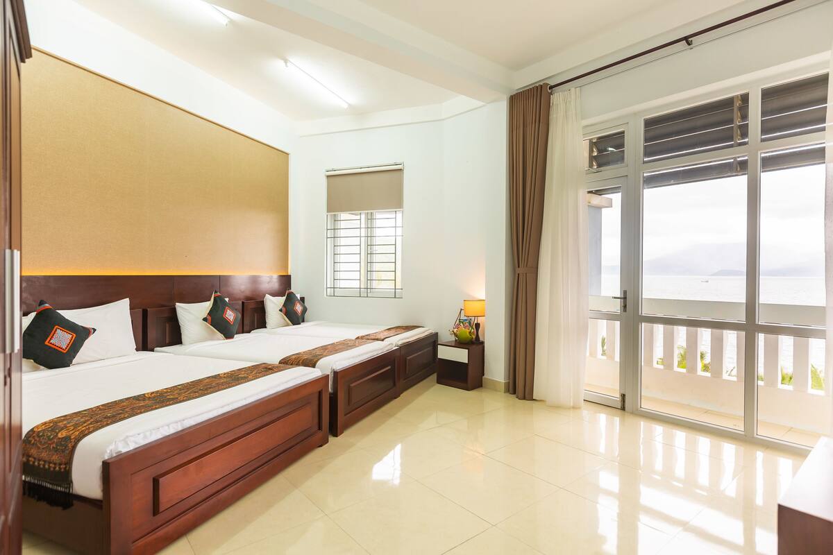 A hotel room with a large bed, a window with a view, and a balcony.