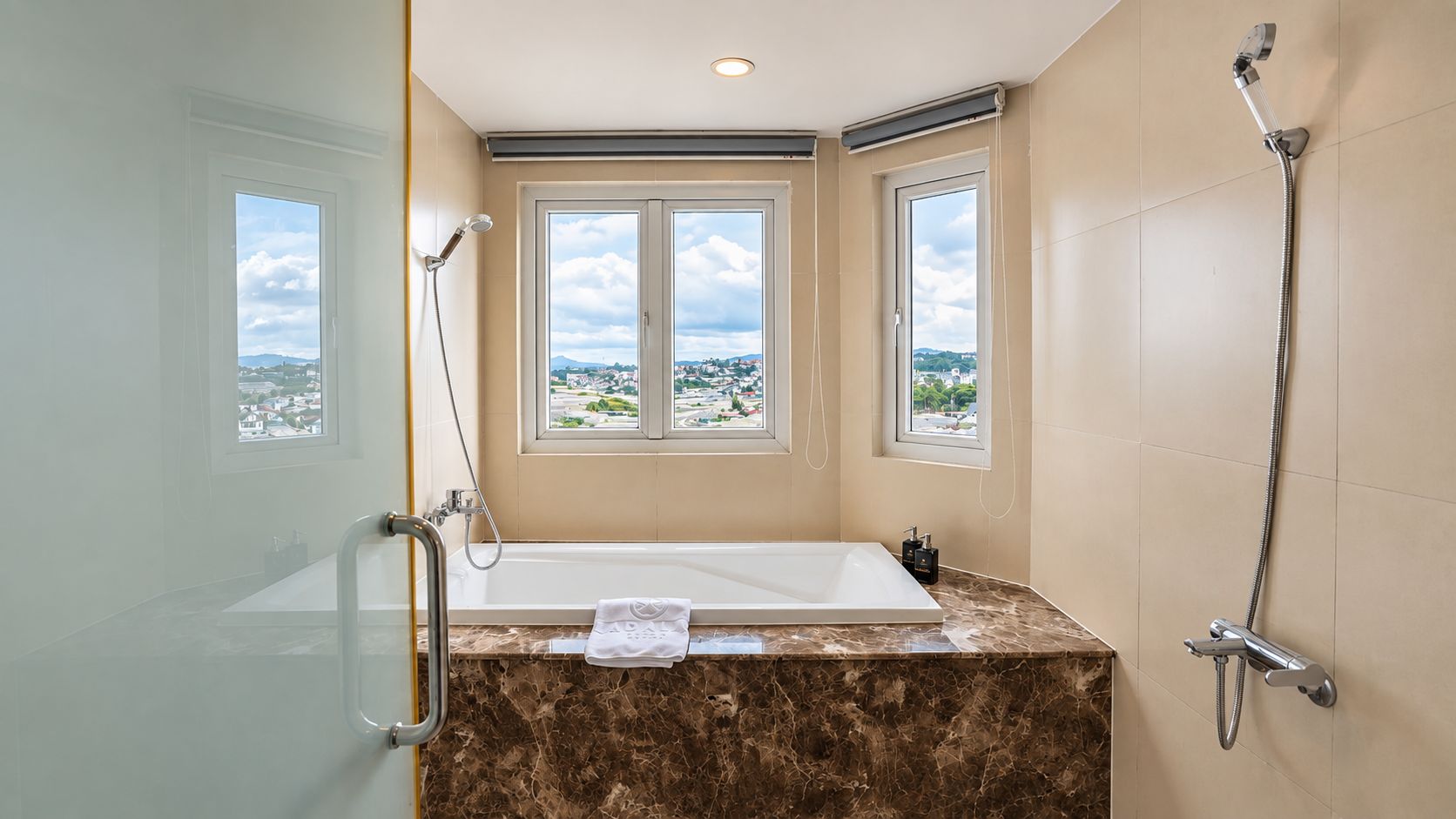 A bathroom with a bathtub, shower, and two windows offering a view.