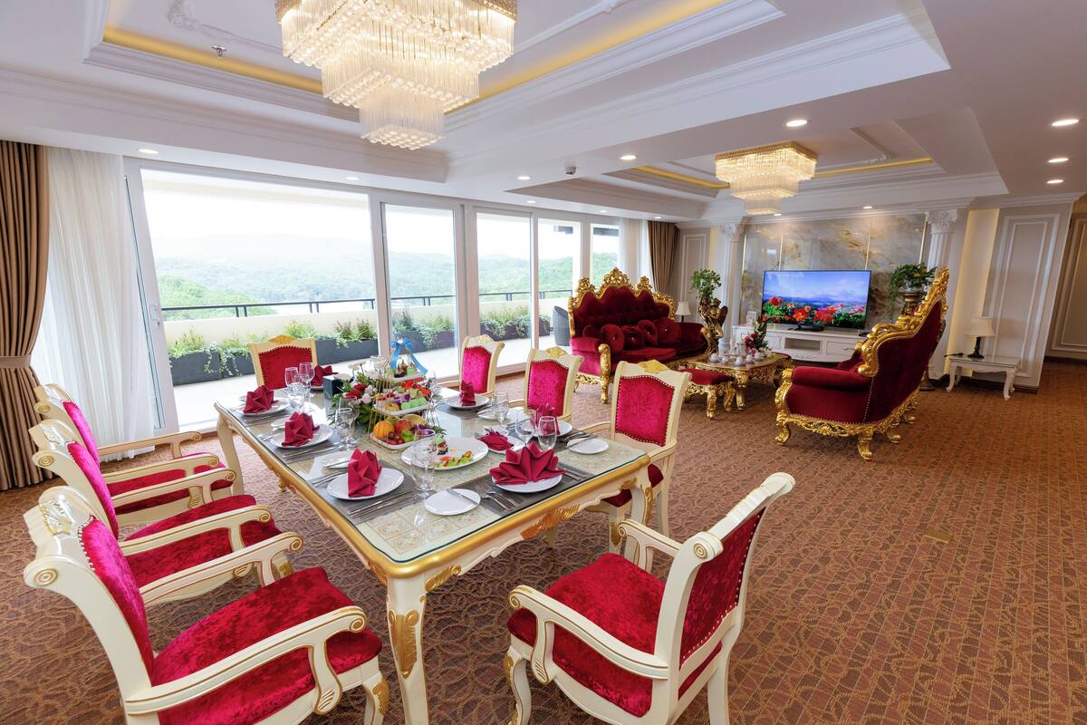 Un comedor con una mesa grande dispuesta para una comida, rodeada de sillas decorativas.