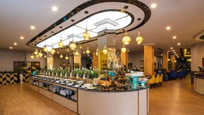 A buffet area with a curved counter, overhead lighting, and a variety of food items. - Ladalat Hotel (Lam Vien - Da Lat)