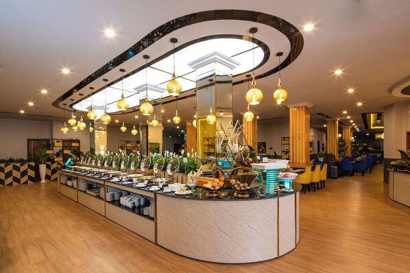 A buffet area with a curved counter, overhead lighting, and a variety of food items. - Ladalat Hotel (Lam Vien - Da Lat)