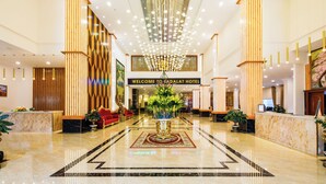 A hotel lobby with a marble reception desk, a central floral arrangement, and a chandelier. - Ladalat Hotel (Lam Vien - Da Lat)