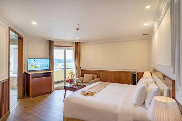 Ein Hotelzimmer mit Bett, Fernseher, Schreibtisch und Blick ins Freie.