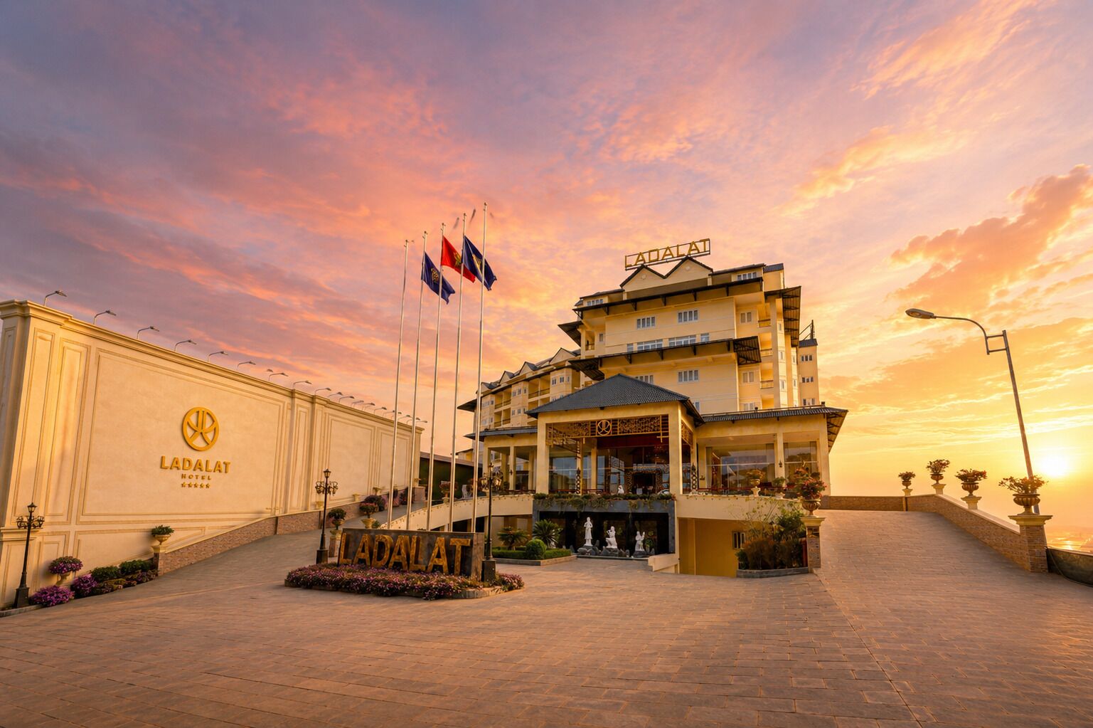 Un hotel con una entrada destacada, varias banderas y cielo despejado.