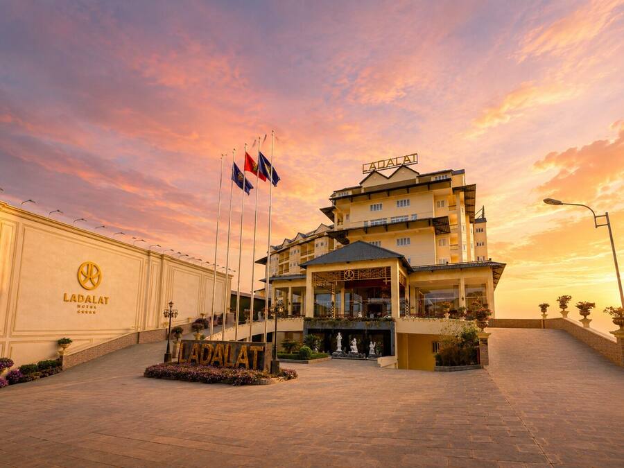 A hotel with a prominent entrance, multiple flags, and a clear sky.