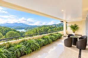 Ein Balkon mit Blick auf einen See und Berge, ausgestattet mit Korbmöbeln und einem Tisch.