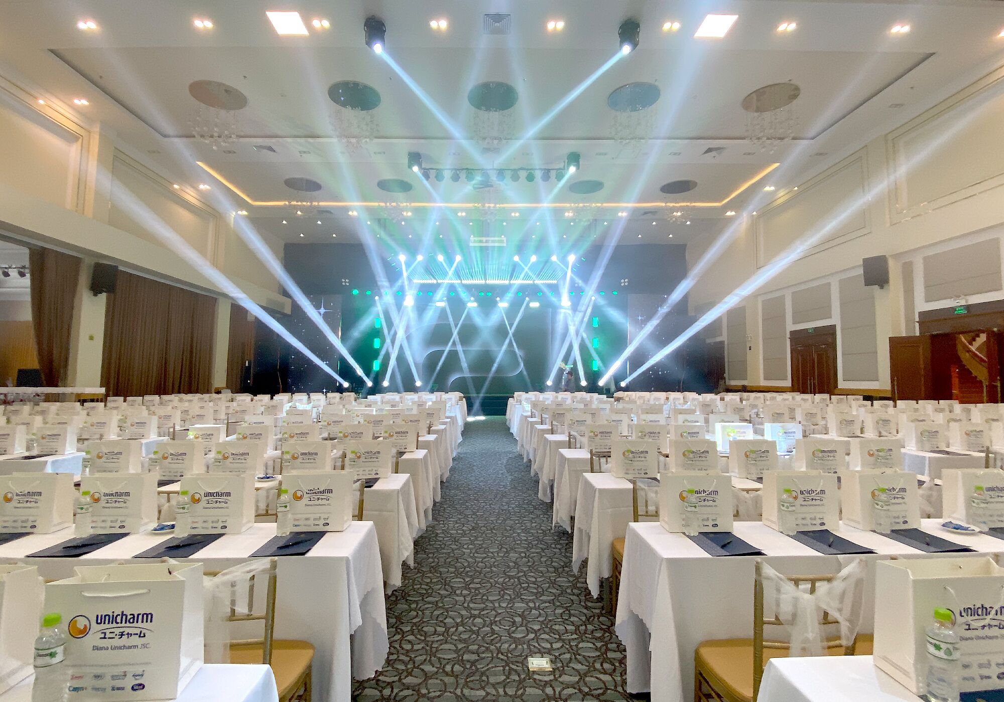 A conference room with rows of tables, each with a name tag and a bottle of water.