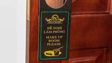 A hotel room door with a card hanger displaying a sign in Vietnamese instructing to make up the room.