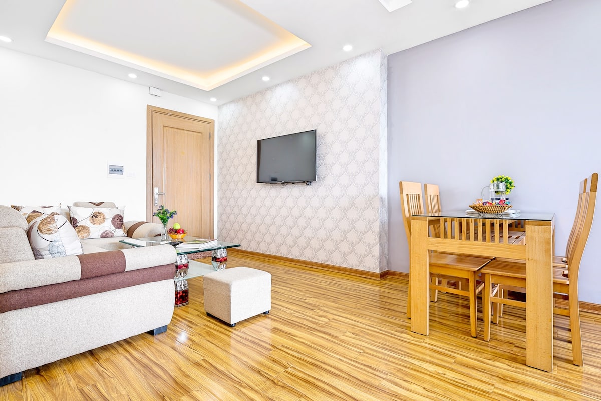 Een moderne woonkamer met een bank, een poef en een eettafel met stoelen.