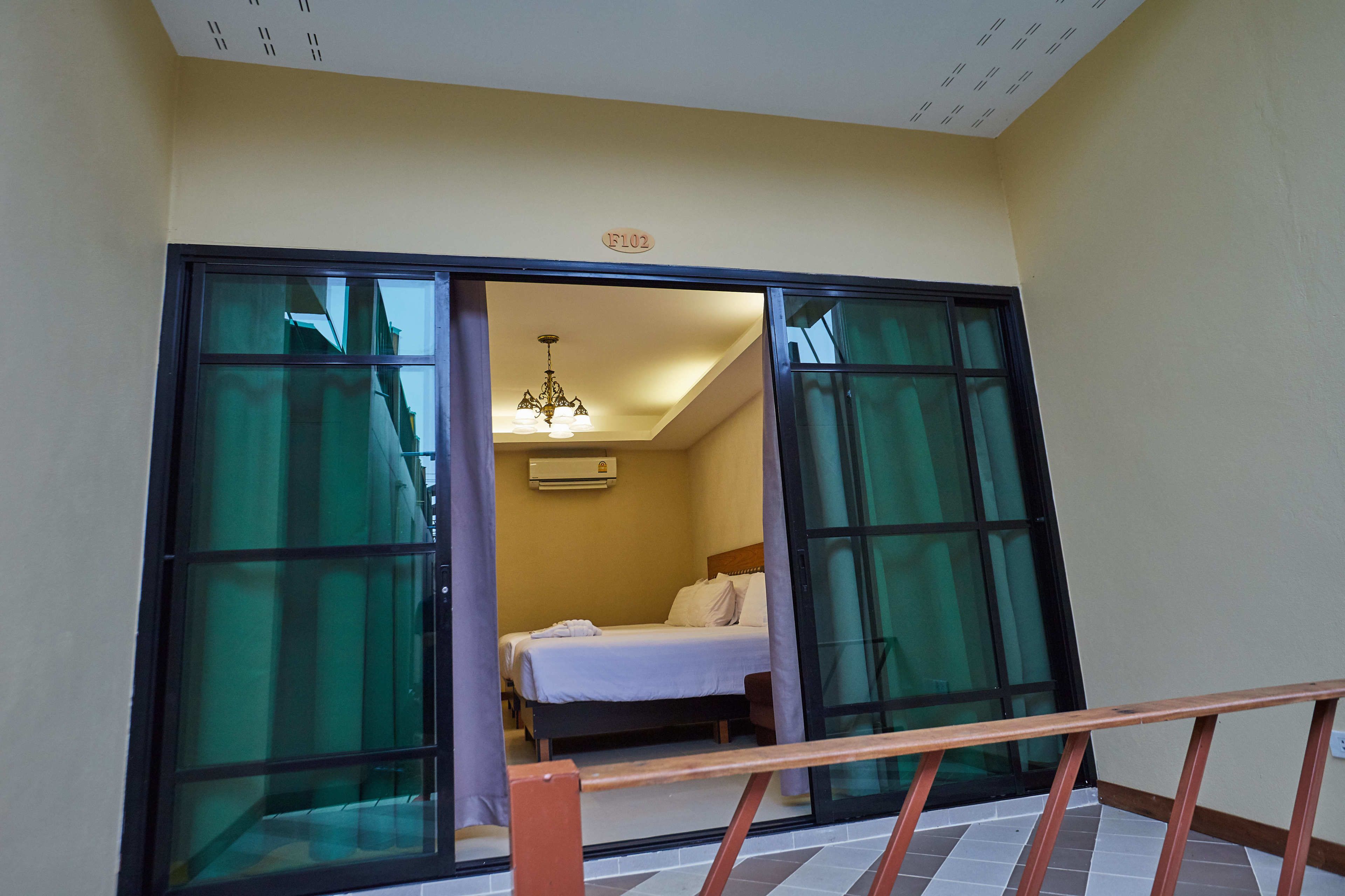 A hotel room with a bed, a ceiling fan, and a window with curtains.