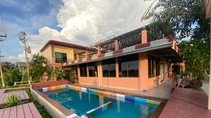 Una casa moderna con piscina, patio cubierto y jardín.