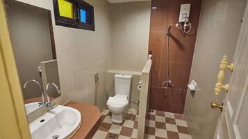 A compact bathroom with a sink, toilet, and shower.