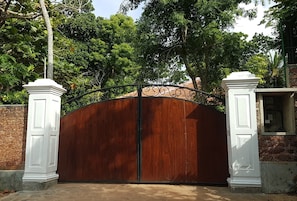 A gated entrance with a wooden gate and decorative white pillars.