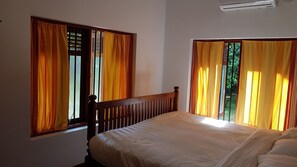 A room with two windows, each with yellow curtains, a wooden headboard, and a bed with white bedding.