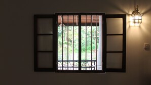 Une fenêtre avec une grille en métal et un luminaire fixé au mur.