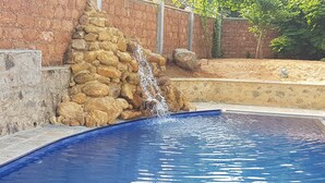 Une piscine agrémentée d’une cascade en pierre et d’un mur en pierre.
