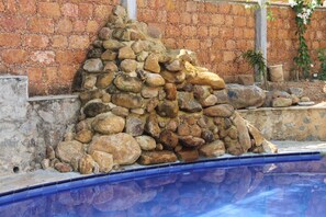 A stone wall with a pool in the foreground.