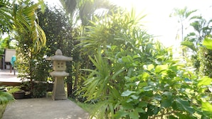 A garden with a stone lantern, a concrete path, and various green plants. - Bangsaray Villa (Sattahip)