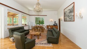A spacious living room with a wooden floor, two green sofas, a wooden coffee table, and a chandelier. - Seehaus Familie Leifer (Sankt Wolfgang im Salzkammergut)