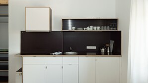A compact kitchen with white cabinets, a black countertop, and a small sink. - Seehaus Familie Leifer (Sankt Wolfgang im Salzkammergut)