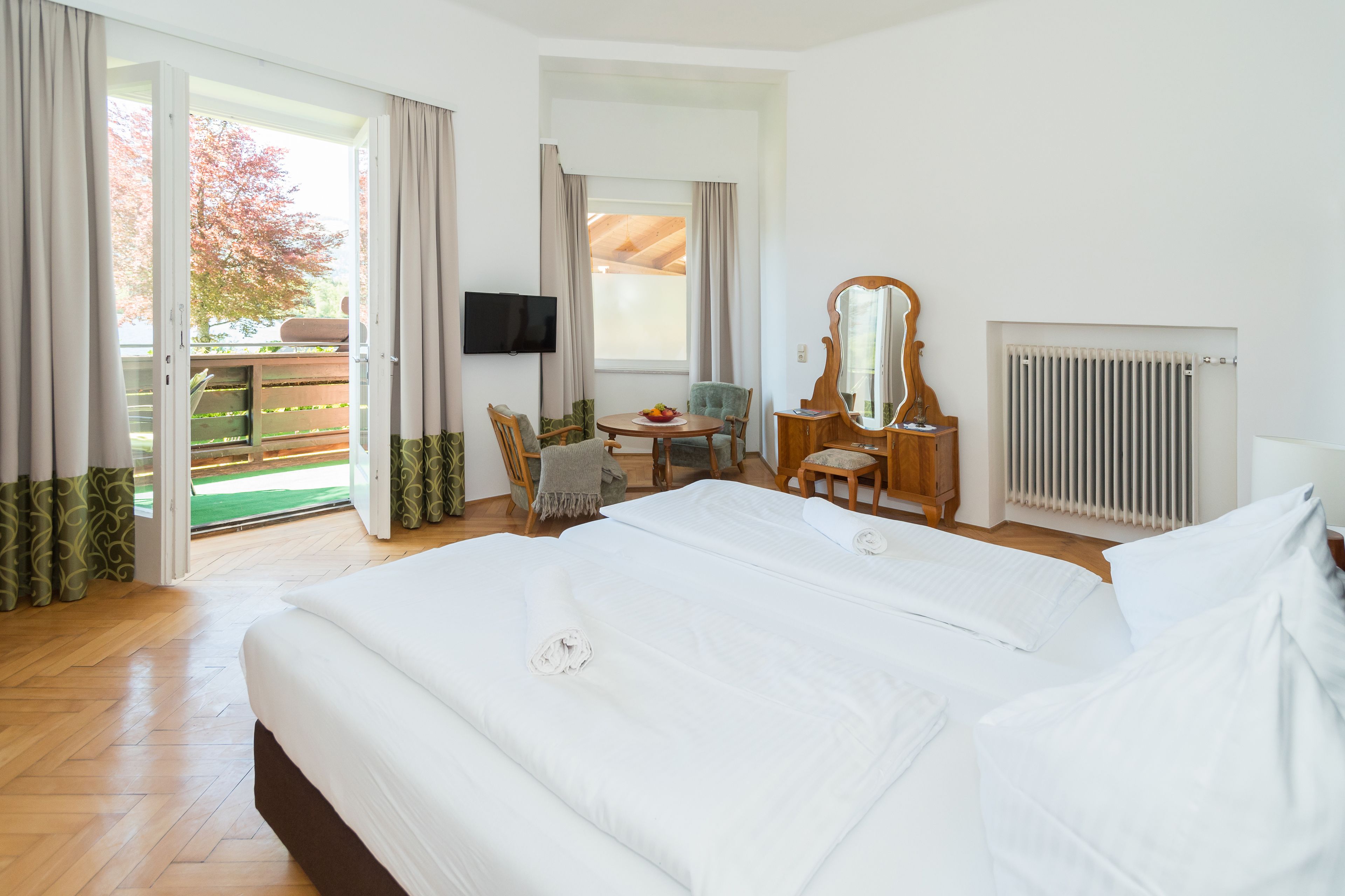 Habitación de hotel con una cama grande, un escritorio con silla, televisión y vistas al exterior.