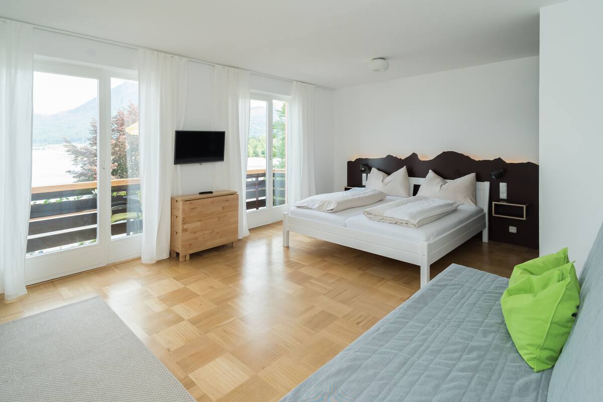 Ein Schlafzimmer mit Bett, Fernseher, Kommode und Balkon mit Bergblick.