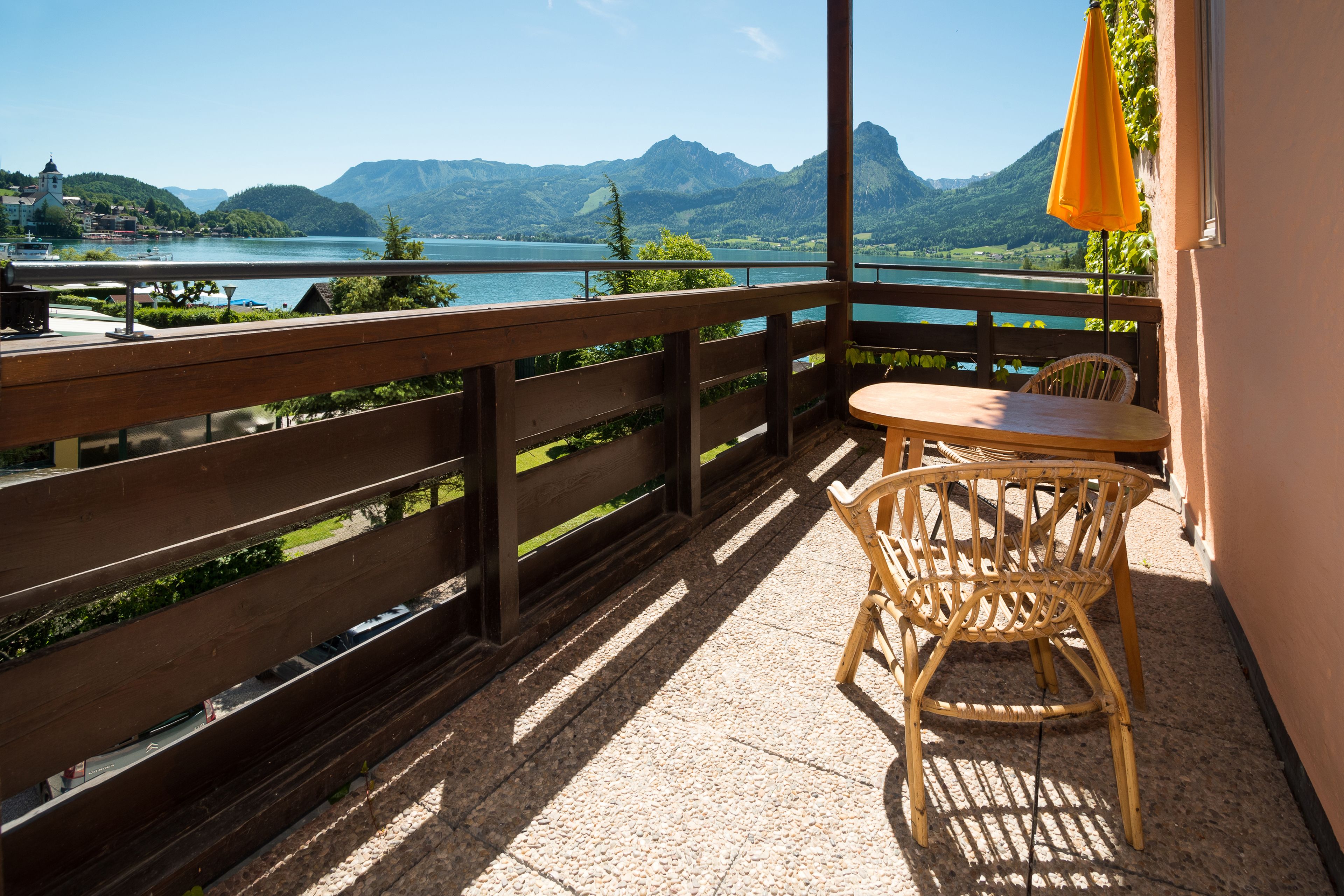 A balcony with a wooden railing, a wicker chair, and a small table.