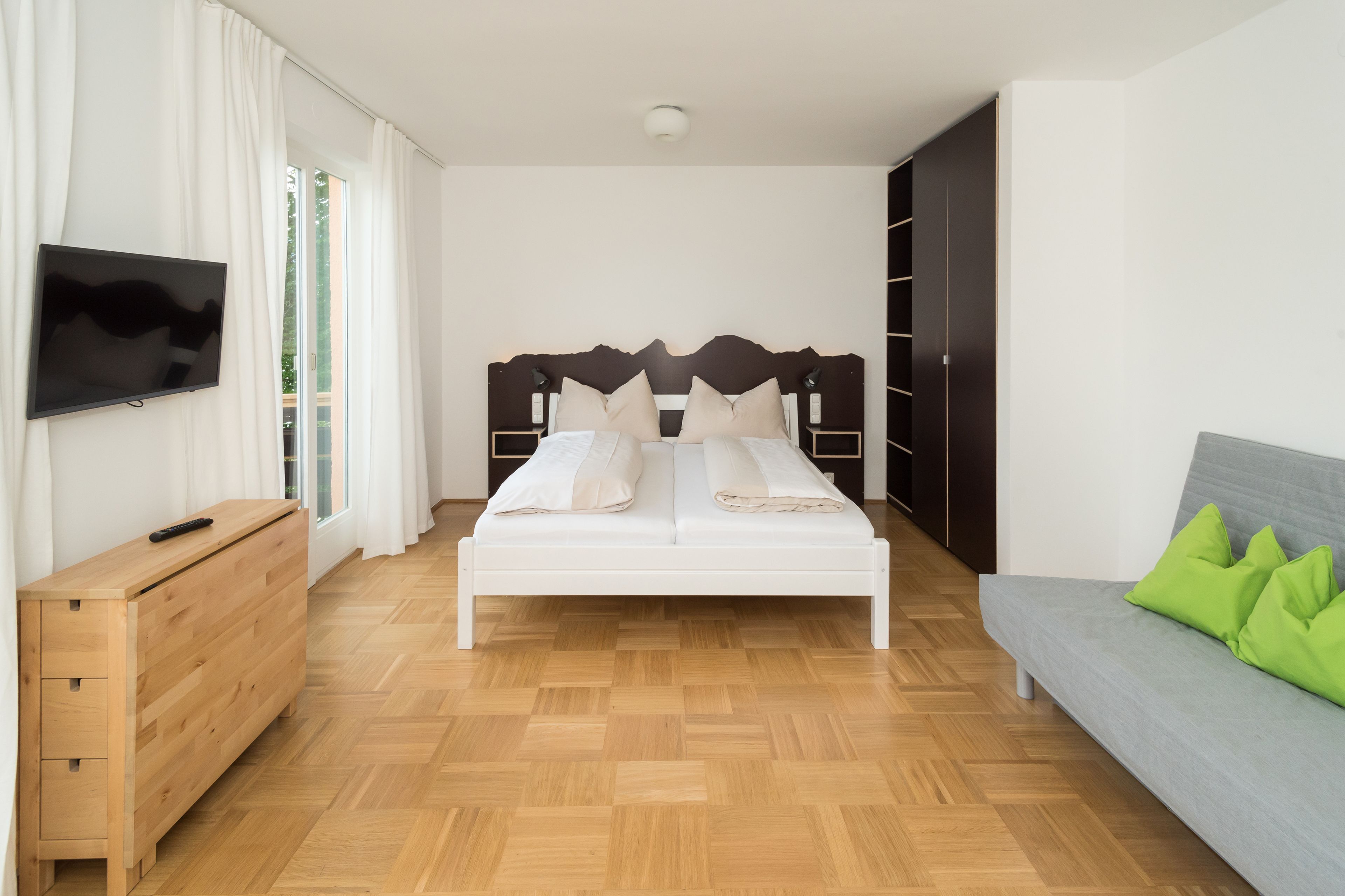 Une chambre à coucher avec un lit, une télévision, une commode et un canapé.
