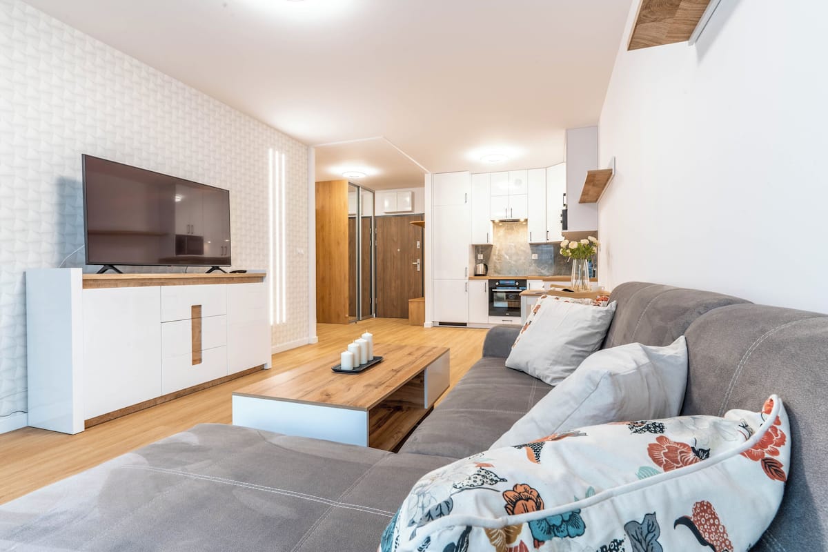 Una sala de estar moderna con un sofá, un televisor y una mesa de centro de madera.