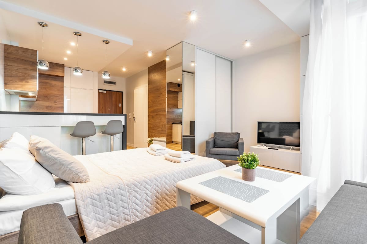 Una habitación de hotel moderna con cama, televisión, zona de estar y kitchenette.