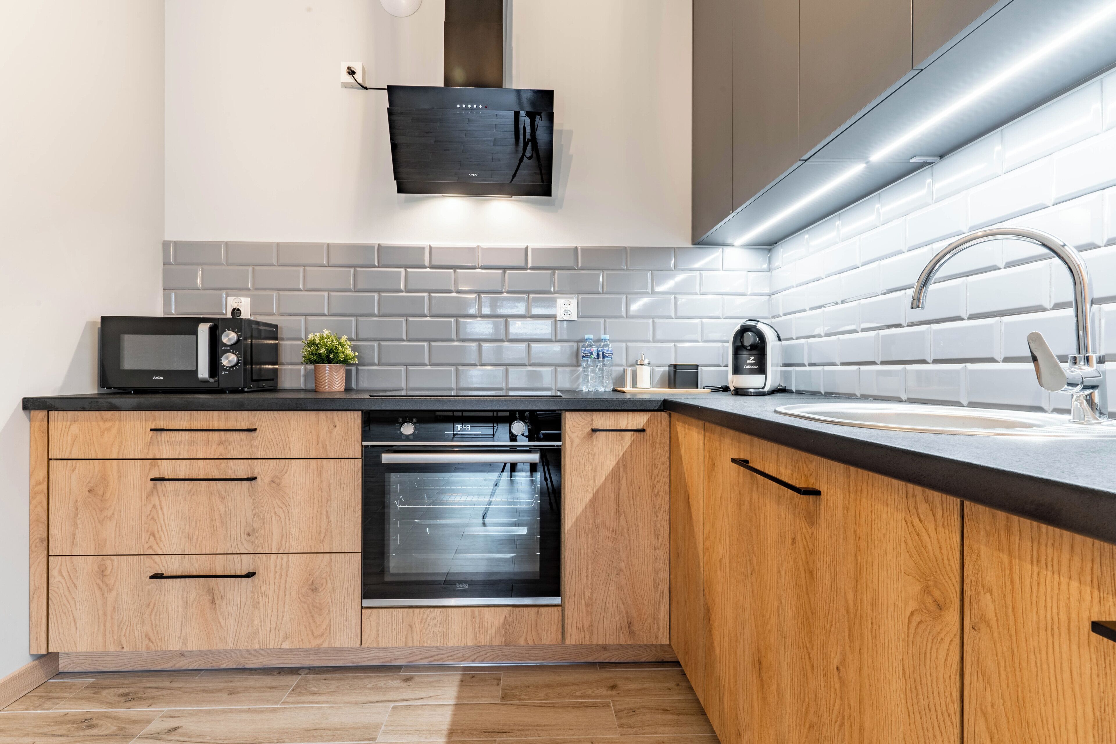 A modern kitchen with a built-in oven, microwave, and a stainless steel sink.