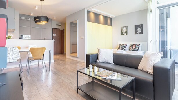 Una sala de estar moderna con sofá, mesa de centro y comedor con sillas.