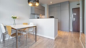 Una cocina moderna con armarios grises, una isla blanca y una zona de comedor con mesa y sillas.