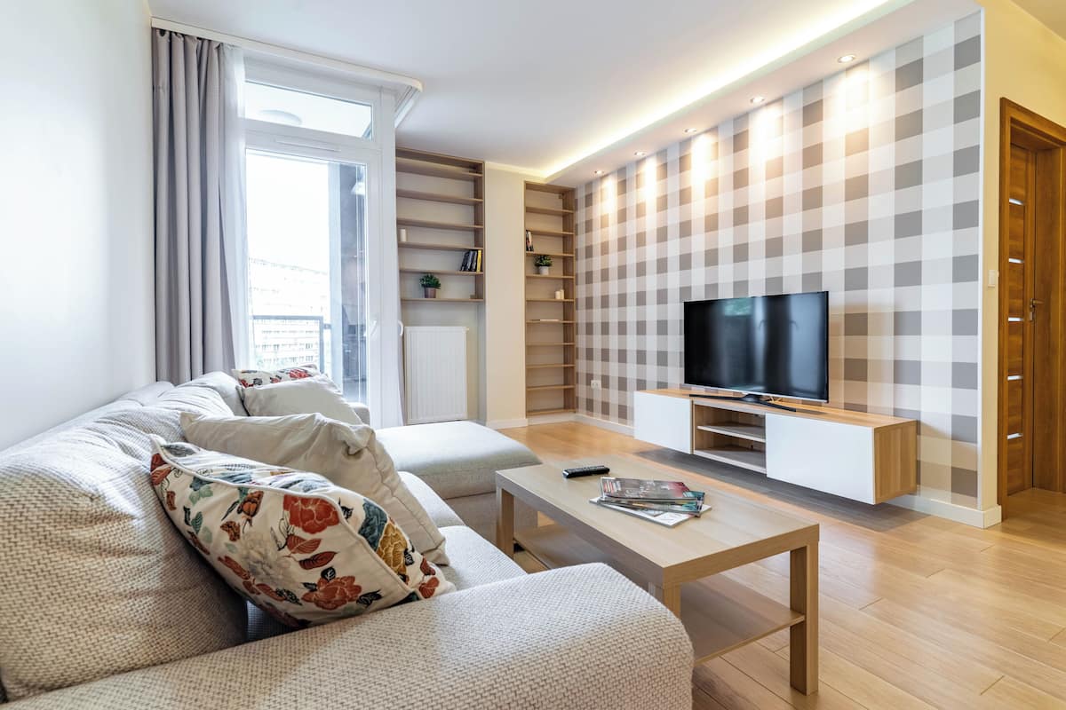 Una sala de estar moderna con sofá, mesa de centro, televisor y estanterías empotradas.