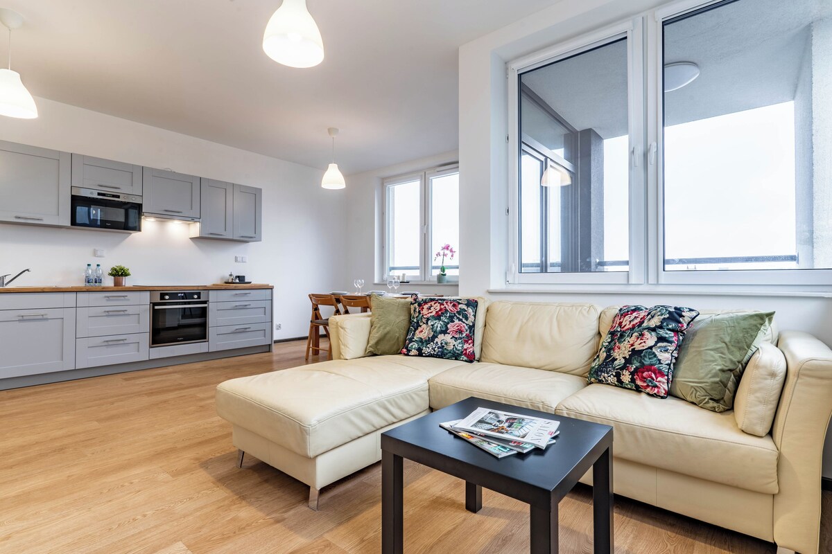 A modern living room with a sofa, coffee table, and a dining area with chairs and a table.